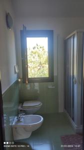 baño con 2 aseos, lavamanos y ventana en ViViHolidays, en Castellammare del Golfo