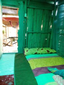 Ce lit se trouve dans un dortoir aux murs verts. dans l'établissement The Rock Hut, à Ko Lanta