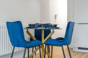 une cuisine avec des chaises bleues et une table dans l'établissement Modern Stylish 1 bedroom apartment in the heart of Potters Bar, à Potters Bar