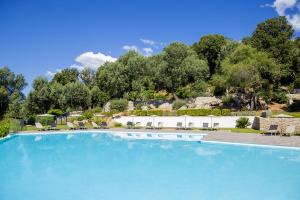 a large blue swimming pool with chairs and trees at Domaine d'Arca - Gauguin 12 - 2 chambres - étage 2 in Porto-Vecchio