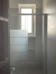 uma casa de banho com uma porta de duche em vidro e uma janela em Gallipoli Il mare in una stanza em Lido Conchiglia
