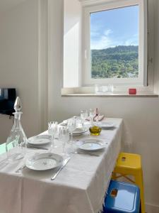 una mesa blanca con platos y gafas y una ventana en Casa Alta, en Castelo de Vide