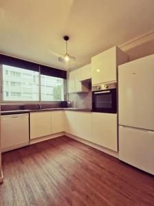 a large kitchen with white cabinets and a refrigerator at T3 Villeurbanne avec balcon in Villeurbanne