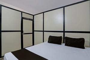 1 dormitorio con cama blanca y almohadas negras en OYO Madhupushpa Farm House, en Rāmtek