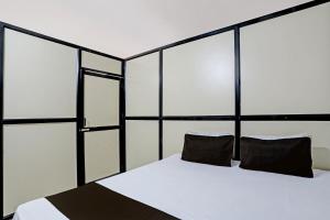 ein Schlafzimmer mit einem Bett mit zwei schwarzen Kissen in der Unterkunft OYO Madhupushpa Farm House in Rāmtek