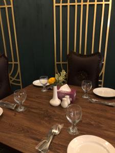 una mesa de madera con platos y copas de vino. en RT Grace Royal Taj Hotel Sukkur, en Kalar Goth