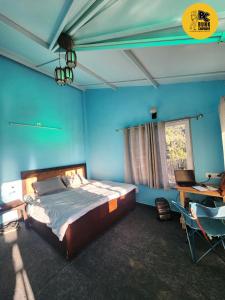 a bedroom with blue walls and a bed and a desk at BUNK CHAMBER in Mukteswar