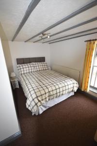 a bedroom with a bed with a checkered blanket at Bank Top Farm Cottages in Stoke on Trent