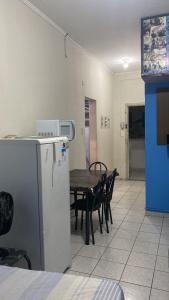 uma sala de jantar com uma mesa e um frigorífico em Kitinete perto da praia e Shopping Brisamar em São Vicente, na Biquinha, temporada e mensal tudo incluso, mobiliado, wi fi, ventilador, elevador, horário flexível em São Vicente