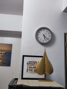 een klok op een muur boven een tafel met een papieren boot bij TriG Place at Grace Residence in Taguig City in Manilla
