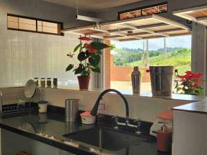 um balcão de cozinha com um lavatório e uma janela em Sítio da Cachoeira em Socorro