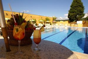 two drinks on a table next to a swimming pool at Paradies Hotel Express in Jarinu