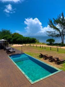 una piscina con mesas de picnic y bancos en una terraza en Lagoon Suites e Gastronomia, en Laguna