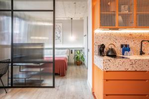 - une cuisine avec des armoires orange et un lit dans une chambre dans l'établissement Coeo Apart-Hotel Parras, à Malaga