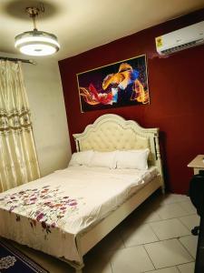 a bedroom with a white bed with a red wall at hongyuanprimierhotel in Accra