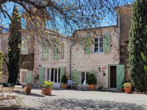 een groot stenen huis met groene luiken erop bij Spacious holiday home with private pool in Cazouls-lès-Béziers