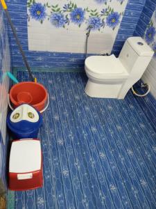 a bathroom with a toilet in a blue tile floor at BUNK CHAMBER in Mukteswar