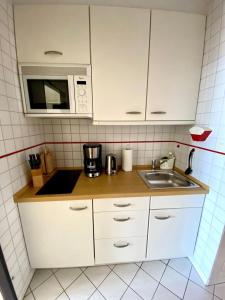 a small kitchen with a sink and a microwave at Suedstrand-Ferienwohnung-Suhr in Burgtiefe auf Fehmarn 