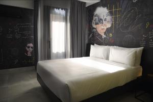 a bedroom with a white bed with a wall with graffiti at SO City Hotel Adults Only in St. Julianʼs