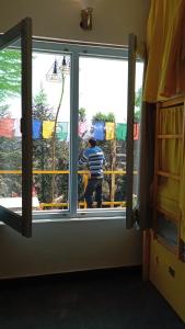 Un homme regarde par une fenêtre dans l'établissement BUNK CHAMBER, à Mukteswar