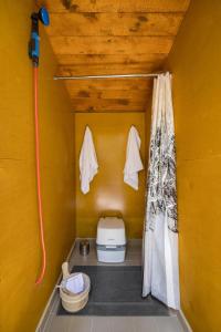 a small bathroom with a toilet in a yellow wall at Stay Wilder Sunshine Coast in Sechelt
