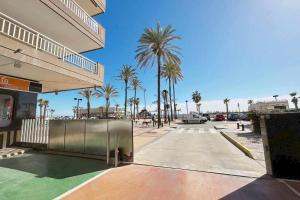 un parking avec des palmiers et un bâtiment dans l'établissement Palm Beach Fuengirola parking piscina Andra, à Fuengirola