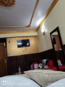 Cette chambre comprend un lit et une télévision murale. dans l'établissement HOTEL MOUNT ROYALE Darjeeling, à Darjeeling