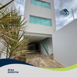 un bâtiment avec un palmier en face dans l'établissement Nox Temporada - Flat 201 a 4km da Feira e Shopping Caruaru, à Caruaru