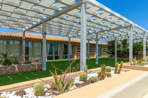 un pergolato bianco in un giardino con cactus di Gravina Resort & Apartments a Costa Paradiso