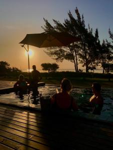 eine Gruppe von Menschen, die bei Sonnenuntergang in einem Pool sitzen in der Unterkunft Lagoon Suites e Gastronomia in Laguna