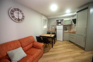 a living room with a couch and a clock on the wall at Apartamentos Parrillada Ourense in Rianjo