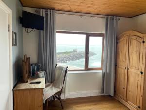 um quarto com uma secretária e uma janela com vista para o oceano em The Coastguard House @ Tigh T.P. em Ballydavid