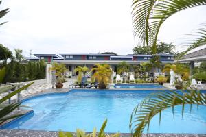 una piscina frente a un complejo con palmeras en MB House Resort, en Ban Nai Rai