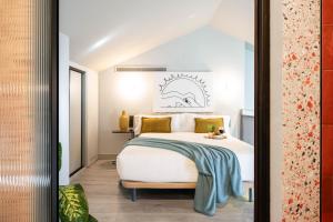 een slaapkamer met een wit bed met een blauwe deken erop bij Coeo Apart-Hotel Parras in Málaga