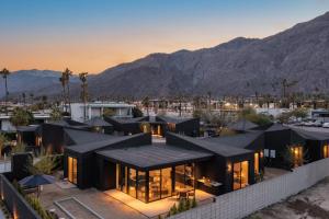 uma casa com um telhado preto com montanhas ao fundo em Blackhaus A B Buyout by AvantStay Sleeps 16 em Palm Springs