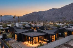 a house with a black roof with mountains in the background at Blackhaus A B Buyout by AvantStay Sleeps 16 in Palm Springs