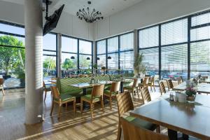 ein Restaurant mit Tischen, Stühlen und Fenstern in der Unterkunft Hotel Alea City in Pfaffenhofen an der Ilm