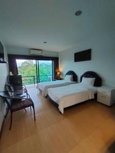 1 dormitorio con 2 camas, silla y ventana en Evergreen Resort Chanthaburi, en Chanthaburi