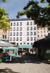 ein großes weißes Gebäude mit einem Markt davor in der Unterkunft Louis Hotel in München