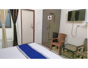 a bedroom with a bed and a chair and a tv at Hotel Radhika Kunj Palace, Chhatarpur in Chhatarpur
