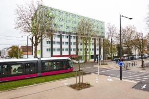 a train on a street in front of a building at Campanile Dijon Congrès Clemenceau in Dijon