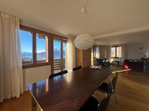 a dining room with a large wooden table and windows at Chalet Friesli Beatenberg in Beatenberg