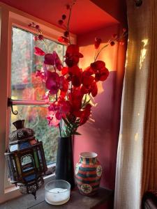 eine Vase mit roten Blumen auf einem Fensterbrett in der Unterkunft Large 4 bed house in Malmesbury, great for big families in Malmesbury