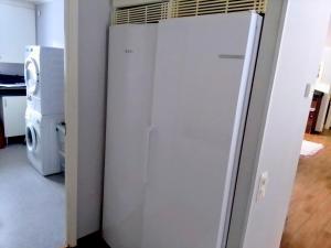 a white refrigerator in a kitchen next to a washing machine at Havsnära villa in Nordmaling