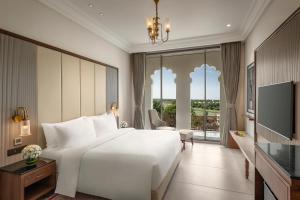 a bedroom with a large white bed and a large window at Uday Palace Navsari, a member of Radisson Individuals in Navsāri