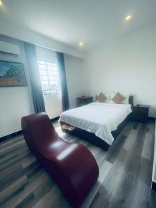 a bedroom with a bed and a leather chair at T ONE II HOSTEL in Can Tho