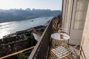 een tafel en stoelen op een balkon met uitzicht op een rivier bij Maison Bleue in Porto