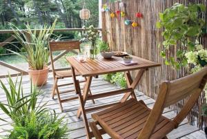 una mesa de madera y sillas en un patio con plantas en Appart Hôtel - Nature et Spa, en Aurons