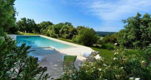 a swimming pool with chairs in a garden at Appart Hôtel - Nature et Spa in Aurons