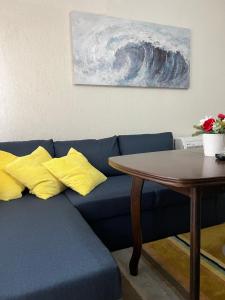 niebieska kanapa z żółtymi poduszkami obok stołu w obiekcie Apartment Kiril and Metodi 41-8А w mieście Berkowica